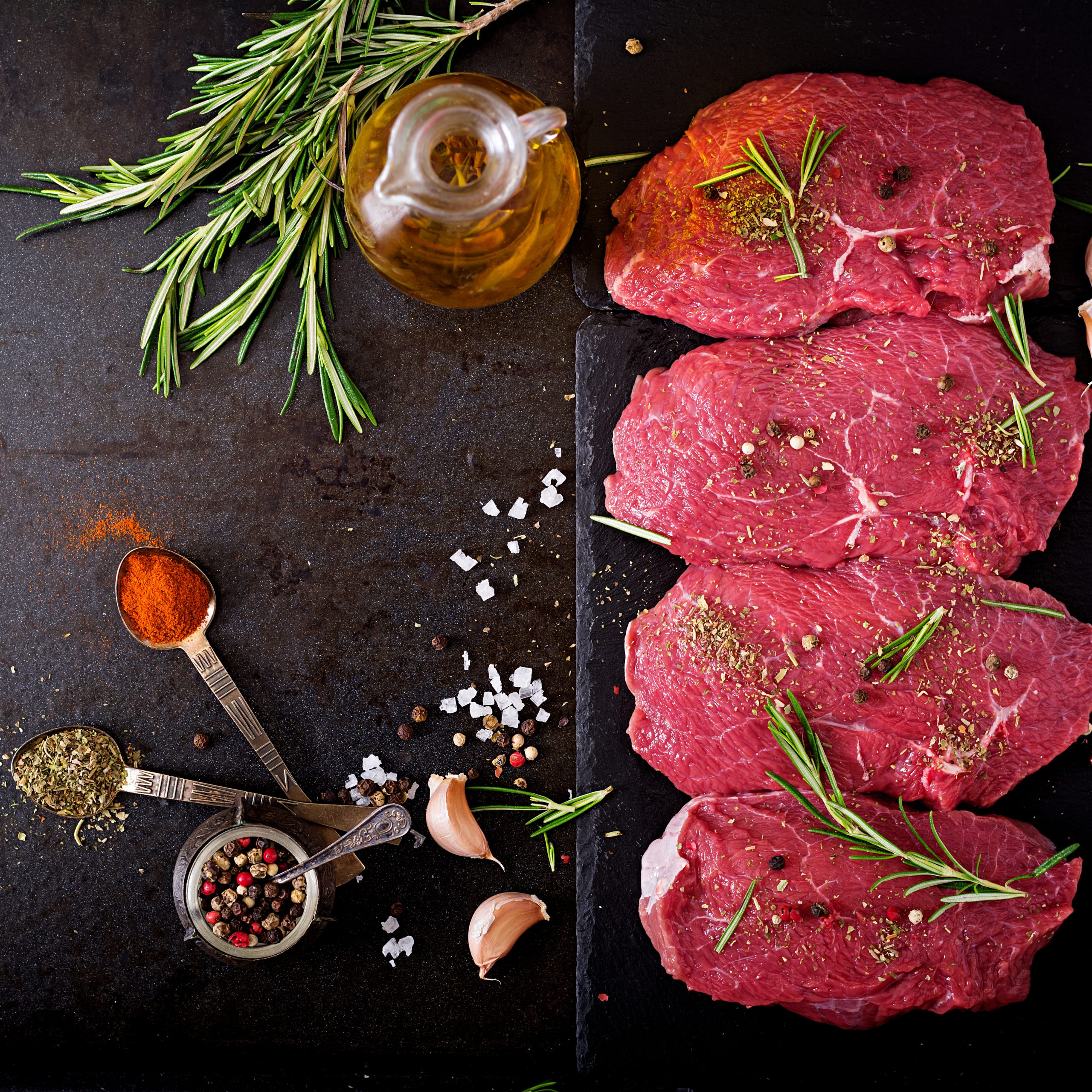 Raw beef steaks with spices and rosemary. Flat lay.Top view Raw beef steaks with spices and rosemary. Flat lay.Top view